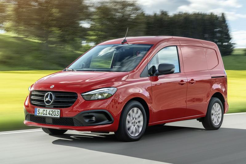 rode Mercedes-Benz bestelwagen rijdt op een weg door groen landschap
