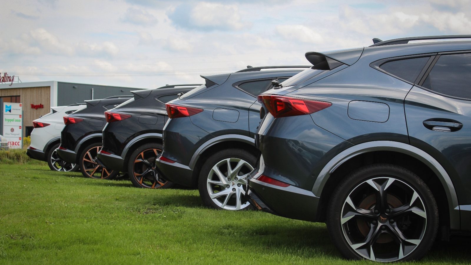 Rij geparkeerde SUV's op gras bij een gebouw