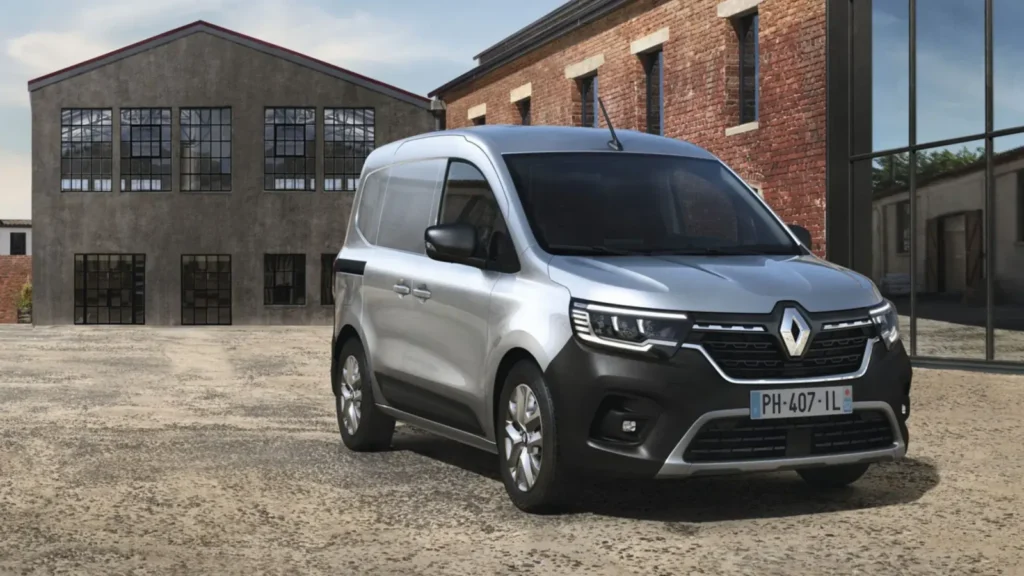 zilverkleurige Renault bestelwagen op een industrieterrein voor bakstenen gebouwen