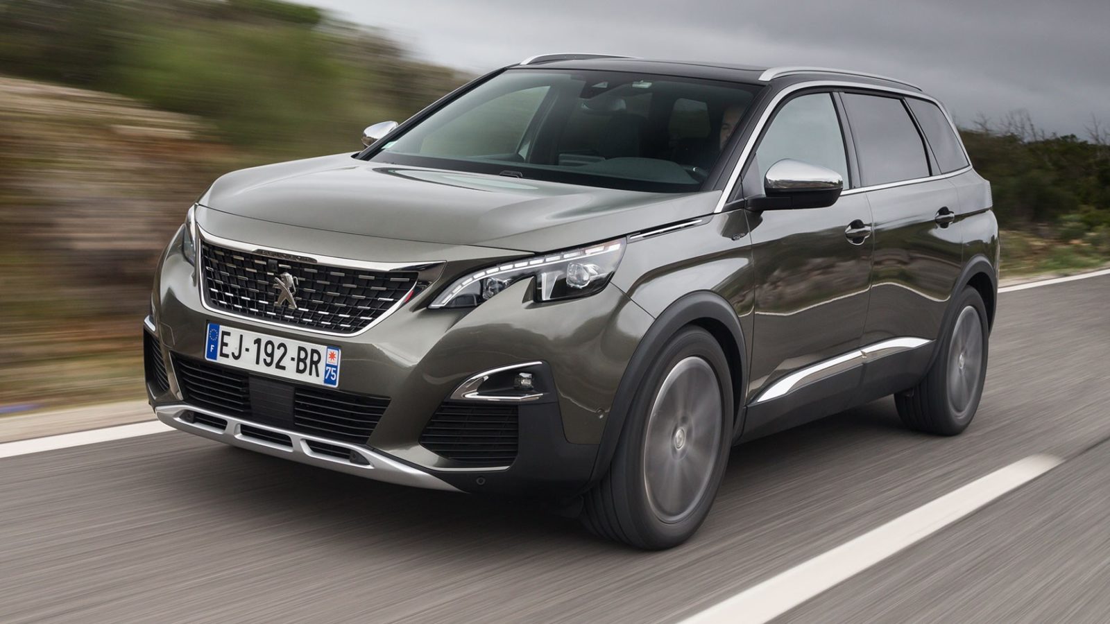 Grijze Peugeot SUV rijdt over een weg, gefotografeerd schuin van voren