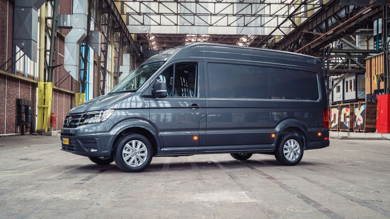 Donkergrijze bestelbus geparkeerd in een lege industriële hal